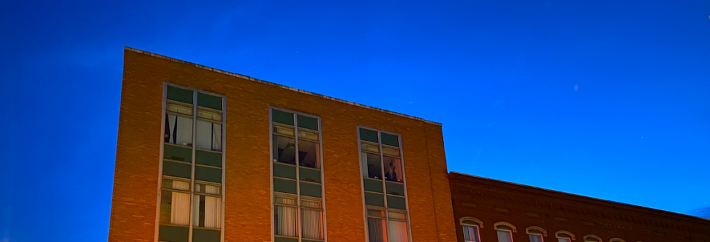 Clear sky behind the silhouette of a brick building with windows.